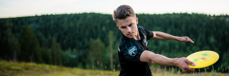 en disc golf spiller kaster en disc med skov i baggrunden