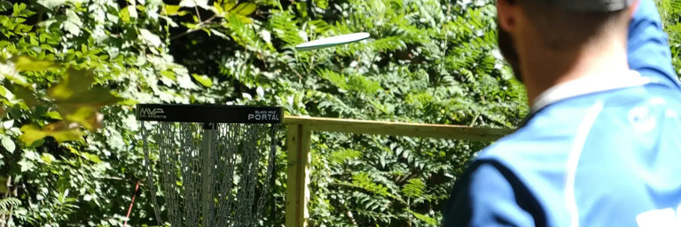 En mand der putter en disc på en sort MVP disc golf kurv