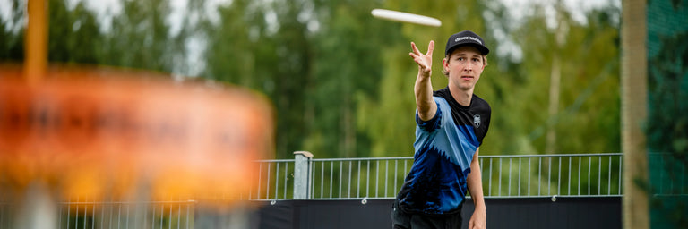 Proffesionel disc golfer Kyle Klein der putter imod en kurv i forgrunden