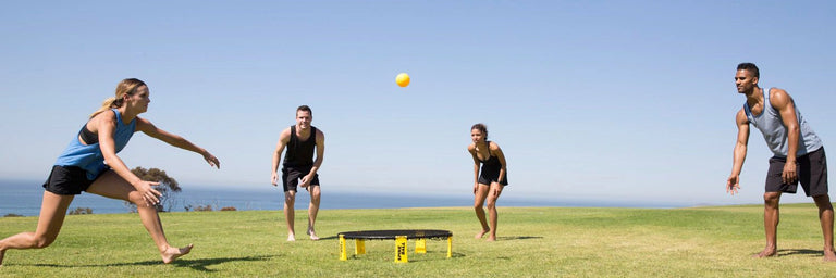 4 personer spiller spikeball på en græsplæne